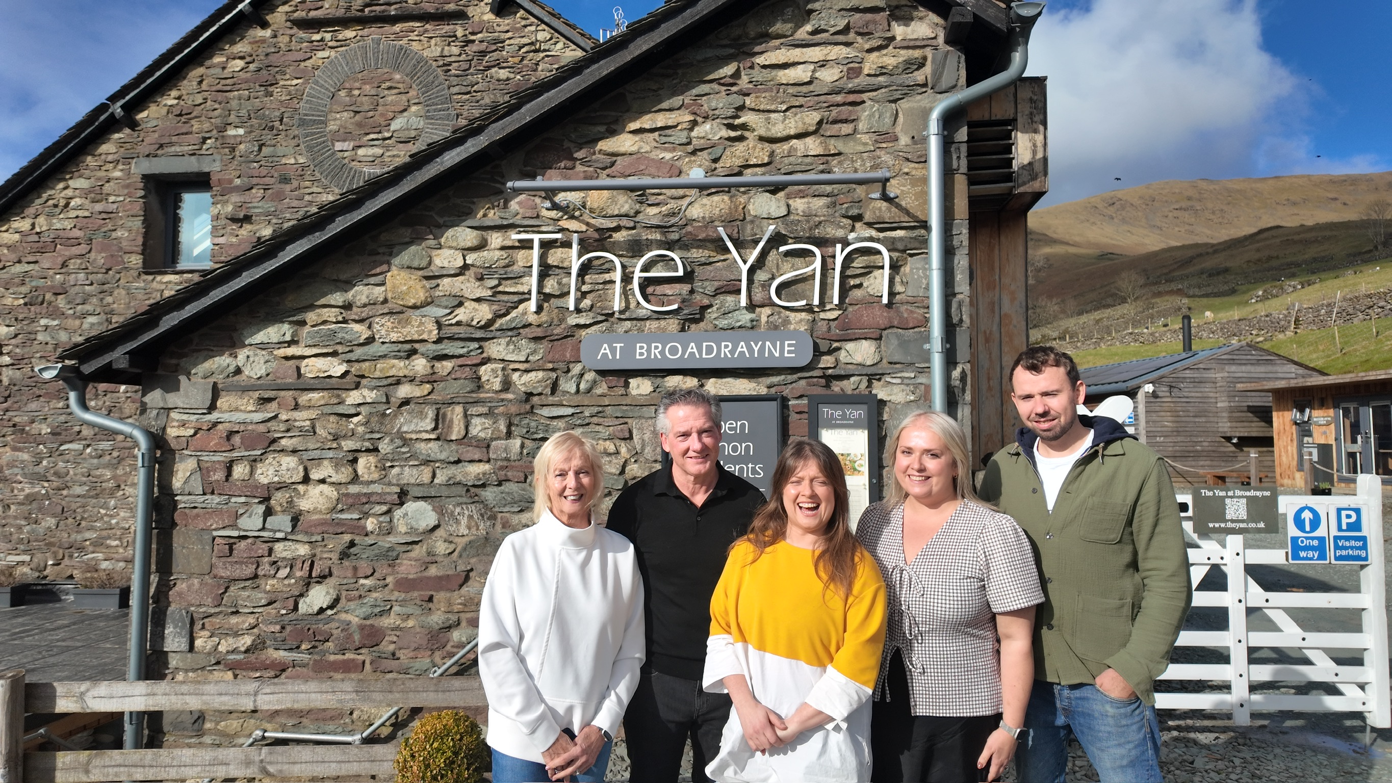 The Yan at Broadrayne family team outside their Lake District hotel and restaurant near Grasmere.The Yan at Broadrayne in Grasmere with snow-covered fells behind - cosy Lake District accommodation for New Year and winter stays.